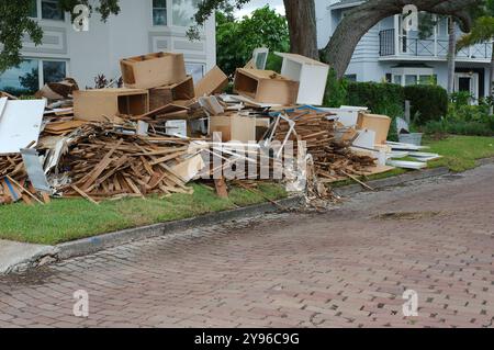 Gros tas de déchets, meubles, articles ménagers empilés sur le côté d'une bordure de rue en briques. Après une tempête endommageant l'inondation d'une onde de tempête d'eau. Attendez Banque D'Images