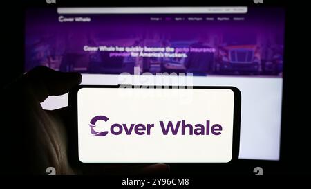 Allemagne. 16 juillet 2024. Dans cette illustration photo, une personne tient un téléphone portable avec le logo de la société américaine Cover Whale Insurance solutions Inc devant la page Web de l'entreprise. Crédit : SOPA images Limited/Alamy Live News Banque D'Images