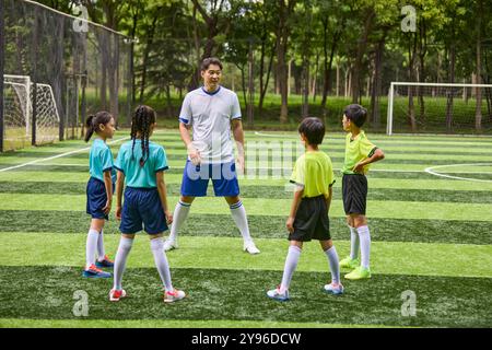 Entraîneur et enfants en cours d'entraînement de football Banque D'Images