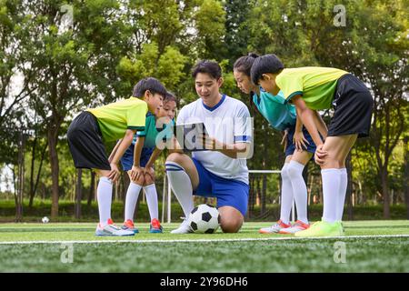 Entraîneur et enfants en cours d'entraînement de football Banque D'Images