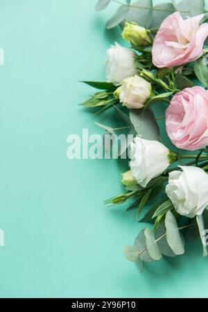 Une belle composition avec de délicates fleurs pastel aux côtés de feuilles d'eucalyptus est placée sur un fond turquoise vibrant. La Fresh Blooms cr Banque D'Images