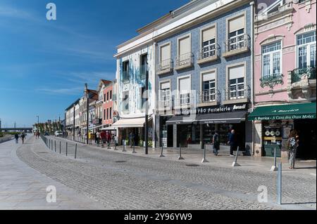 Aveiro, Portugal - 11 septembre 2024 : les piétons se promènent le long d'un chemin pavé bordé de bâtiments colorés par une journée ensoleillée. Banque D'Images