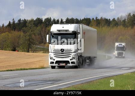 Les camions blancs Mercedes-Benz Actros et Volvo tracent des semi-remorques le long de la route 52 par un jour pluvieux du printemps. Salo, Finlande. 12 mai 2022. Banque D'Images