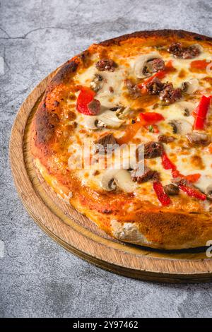 Pizza avec paprika et rôti de bœuf sur planche à découper sur table en pierre Banque D'Images