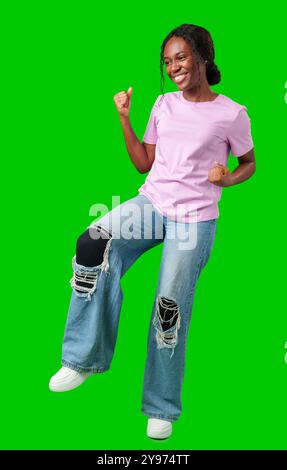 Une jeune femme avec des tresses exprime l'excitation avec un poing serré sur un fond vert vif Banque D'Images