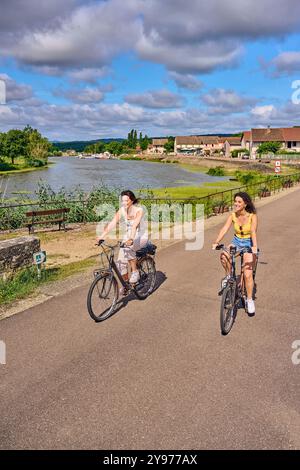 Vélo le long des rives de la Seille, un affluent du Saône à la Truchère (centre-est de la France). Deux jeunes femmes sur des vélos électriques sur un Banque D'Images