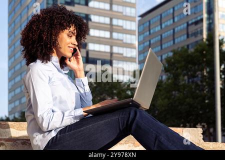 femme assise dans le parc et travaillant à distance Banque D'Images