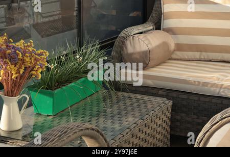 Meubles de patio en osier sur la terrasse en bois dans la journée ensoleillée d'été. Salon de jardin pour se détendre. Banque D'Images