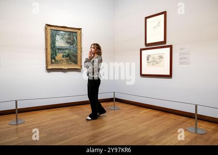 AMSTERDAM - 09/10/2024, Une femme regarde les œuvres la route du lac de Paul Cézanne et étude d'un arbre et d'un paysage avec des arbres et des bâtiments de Paul Cézanne de la nouvelle exposition vive l'impressionnisme! Au musée Van Gogh. L’exposition présente les plus belles œuvres impressionnistes françaises issues de collections néerlandaises. ANP ROBIN VAN LONKHUIJSEN pays-bas OUT - belgique OUT Banque D'Images