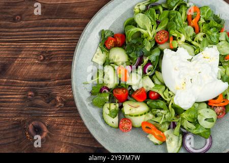 Salade de légumes verts, tomates, concombres et fromage à la crème frais Burrata. Salade Burrata avec des légumes sur une table en bois rustique Banque D'Images