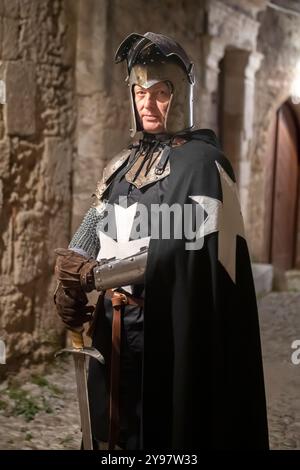 Un portrait d'un Chevalier de préparation John comme il tient une épée tout en se tenant dans une rue médiévale la nuit Banque D'Images