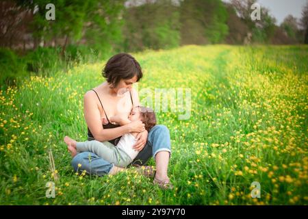 Mère et petite fille fille jouant dans un champ de fleurs au printemps. Concept de maman et fille se liant et jouant ensemble à l'extérieur, tourné avec vintag Banque D'Images