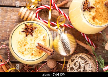 Boisson de Noël avec des bâtons de cannelle et des étoiles d'anis, deux verres de cocktail de lait de poule classique doux à Noël, fond décoré du nouvel an avec fi Banque D'Images