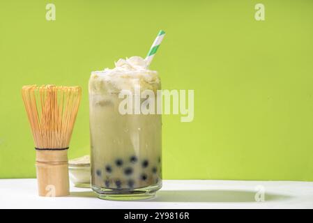 Thé à bulles vert matcha boba avec perle de tapioca. Boisson glacée froide asiatique tendance avec boules de tapioca foncées et crème fouettée non laitière, espace copie Banque D'Images