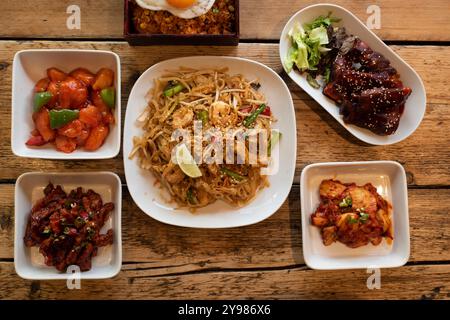 Sélection de plats asiatiques, notamment pad Thai, poulet aigre-doux, ailes de barbecue épicées coréennes et kimchi Banque D'Images