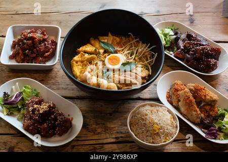 Sélection de plats asiatiques comprenant du curry Laksa, du poulet aigre-doux, des ailes de barbecue épicées coréennes et du kimchi Banque D'Images