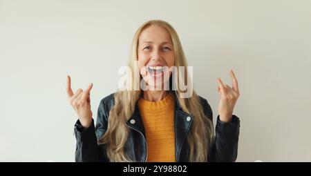 Portrait de femme mature émotionnelle heureuse ravie d'expression folle faisant symbole rock avec les mains vers le haut, havre féminin d'âge moyen à la mode Banque D'Images