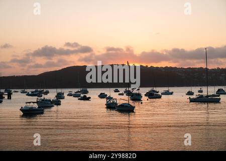 Coucher de soleil à Collins Beach à Manly avec de petites bottes sur l'eau calme devant le soleil couchant (Sydney, Australie) Banque D'Images