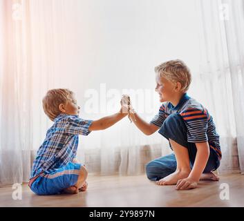 Petit garçon, frère et jouer avec des jouets sur le sol pour lier, week-end ou enfance ensemble à la maison. Enfants, enfants ou frères et sœurs appréciant l'action Banque D'Images