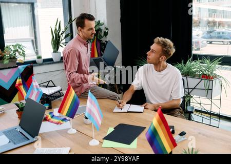 Un couple s'engage dans une séance de brainstorming animée entourée de décorations colorées de fierté. Banque D'Images