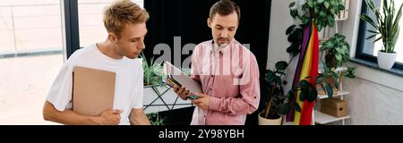 Deux hommes branchés échangent des idées tout en étant entourés de verdure et de décor vibrant dans leur espace de travail. Banque D'Images