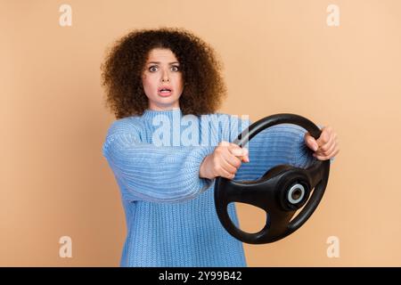 Portrait photo de jeune conducteur de voiture de femme stressé tenant le volant choc accident dans la circulation isolé sur fond de couleur beige Banque D'Images