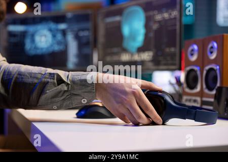 Concentrez-vous sur les écouteurs avec IA sensible en arrière-plan flou interagissant avec un ingénieur en informatique. Gros plan du périphérique audio sur le bureau à côté de l'intelligence artificielle consciente sur l'ordinateur en train de devenir vivant Banque D'Images