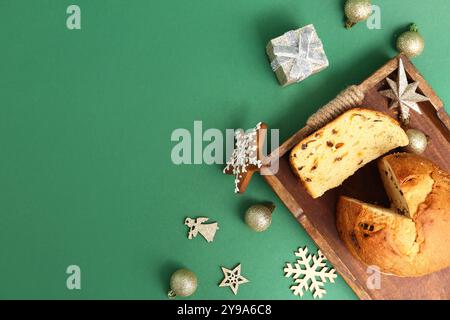 Plateau en bois avec Panettone savoureux et décor de Noël sur fond vert Banque D'Images
