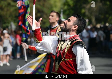 Badacsony, Lac Balaton, Hongrie - 8 septembre 2024 : défilé de rue du festival des vendanges, jeune homme jetant et attrapant le drapeau Banque D'Images