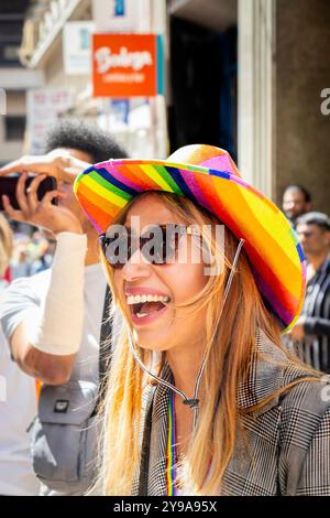 Riant jeune femme à Pride Birmingham portant un chapeau couleur arc-en-ciel et des lunettes de soleil Banque D'Images