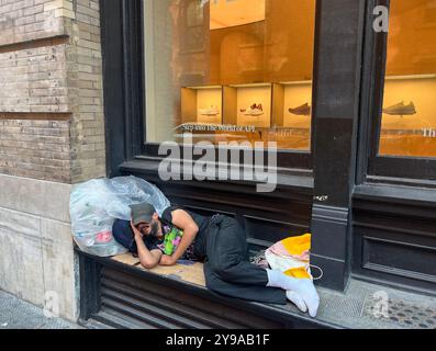 Homme sans-abri dort sur un rebord devant un rivage dans le quartier SOHO de Manhattan, New York City. Banque D'Images