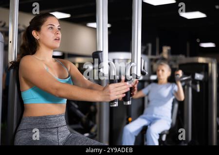 Fille effectuant l'exercice de papillon pour la poitrine dans la machine de plate-forme pec Banque D'Images