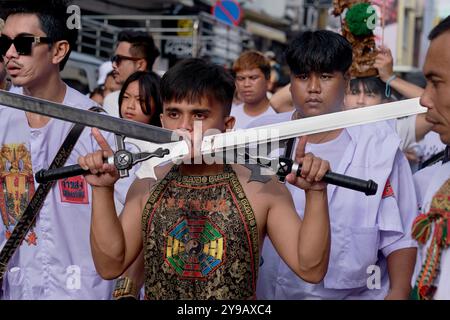 Pendant le Festival végétarien à Phuket Town, en Thaïlande, un Mah Song ou Spirit medium affiche deux grandes épées percées à travers sa joue Banque D'Images