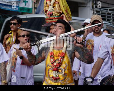 Pendant le Festival végétarien à Phuket Town, en Thaïlande, un Mah Song ou Spirit medium affiche deux grandes épées percées à travers sa joue Banque D'Images