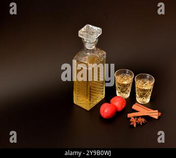 Liqueur de prunes, alcool maison fort dans la verrerie en cristal, cannelle, anis et fruits mûrs sur fond noir. Gros plan. Banque D'Images