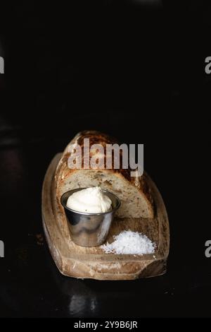 Pain fait maison fraîchement cuit avec du beurre et du sel sur une planche de bois. Banque D'Images