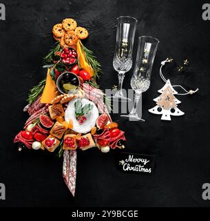 Arbre de Noël à partir de fromages et d'apéritifs de viande sur un fond sombre. Collation des vacances d'hiver. Vue de dessus. Banque D'Images