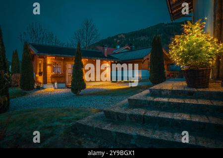 Une maison de chalet en bois confortable près de la station de ski en hiver. Les maisons sont éclairées la nuit, créant une atmosphère chaleureuse et chaleureuse. Vacances de Noël Banque D'Images