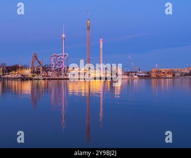 Stockholm, Suède - 20 avril 2023 : parc d'attractions Gröna Lund à Stockholm à l'heure bleue au début du printemps avec manèges illuminés et refl Banque D'Images