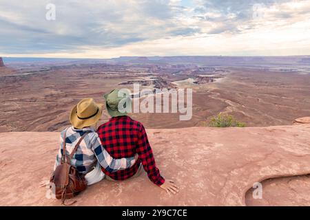 Couple avec vue panoramique sur Buck Canyon vu de Mesa Arch près de Moab, Canyonlands National Park, San Juan County, Utah, États-Unis. Regarder le nid naturel Banque D'Images