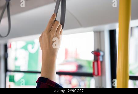 gros plan d'une main tenant une poignée ou un anneau de poignée sur le bus. Guide de voyage de sécurité et concept de transport. Banque D'Images