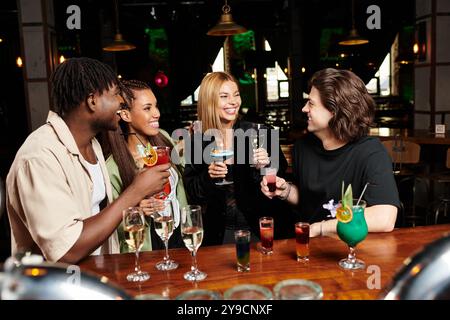 De jeunes collègues portent un toast joyeux avec des boissons colorées lors d'un événement d'entreprise animé. Banque D'Images