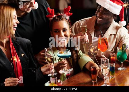 Les jeunes professionnels lèvent joyeusement des verres, célébrant ensemble lors d’un événement corporatif festif. Banque D'Images