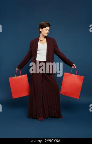 Une femme gracieuse habillée dans la mode hivernale confortable affiche fièrement des sacs à provisions vibrants. Banque D'Images