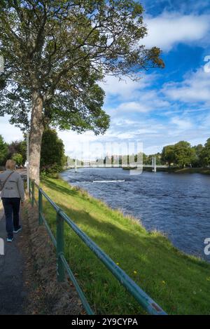 Regardant de l'autre côté de la rivière Ness et descendant vers le centre d'Inverness. Montrant les gens traversant un pont à maillons de chaîne blancs à River Ness Island Walk, le célèbre Banque D'Images