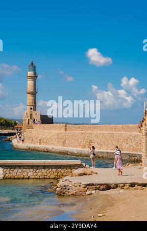 Vacances méditerranéennes, vue arrière de jeunes femmes visitant le long de la digue pittoresque du port vénitien à Chania (Hania) Crète, Grèce Banque D'Images