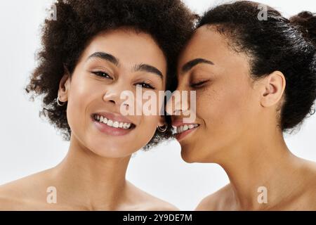 Deux femmes partagent des sourires joyeux dans un espace lumineux, soulignant leur amitié étroite. Banque D'Images