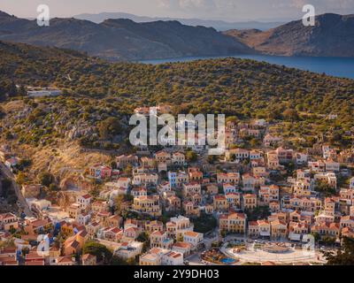 Île de Symi, Grèce - 20 avril 2023 : l'île de Symi est une petite île du Dodécanèse, qui étonne les visiteurs avec une atmosphère calme. Maisons néoclassiques colorées sur les collines de l'île pendant le coucher du soleil. Banque D'Images