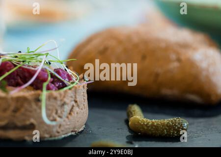 Tartare de bœuf gastronomique avec herbes fraîches et cornichons sur une table en bois rustique. Banque D'Images