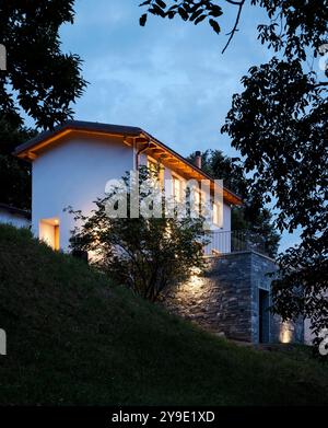 Maison individuelle juste rénovée, avec des finitions modernes. Arrière de la maison avec grand jardin verdoyant privé. Scène de nuit, personne à l'intérieur Banque D'Images